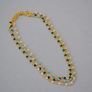 Detailed view of layered gold chain necklace with turquoise, black and pink beads