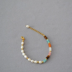 Close-up of pearl and colorful gemstone necklace with gold lobster clasp and extension chain
