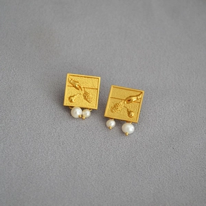 Détail des boucles d'oreilles dorées gravées en relief avec pendentifs perles d'eau douce
