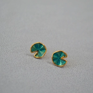 Detailed macro view of green enamel lotus leaf earrings with gold-plated edges and texture