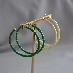 Detail view of colorful enamel bamboo hoop earrings in dark green and cream white colors