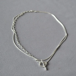 Close-up of a double-layered silver snake and box chain with a classic OT toggle clasp