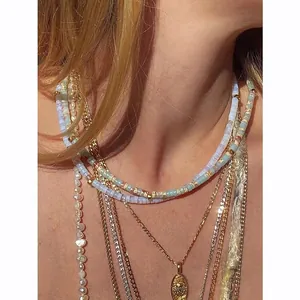 Close-up of layered bohemian necklaces with pearls, blue beads and sunburst gold pendant