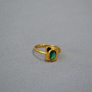 Gros plan détaillé d'une bague vintage en laiton doré avec une émeraude ovale verte