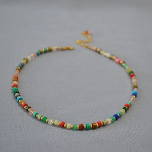 Detailed close-up of bohemian colorful beads and golden spacer beads on a textured surface