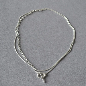 Close-up of double-layered silver necklace featuring a sleek snake chain and T-bar toggle closure