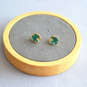 Detail of green enamel lotus leaf earrings with gold edges on wooden display