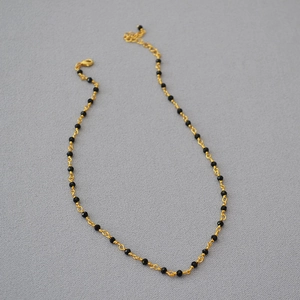Detail of gold choker with black spinel beads featuring lobster clasp and extension chain