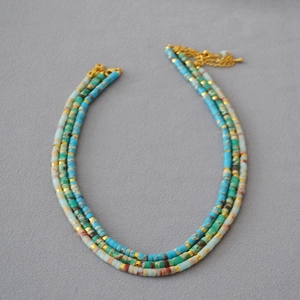 Close-up of bohemian triple-layered colorful heishi bead necklace with gold spacers