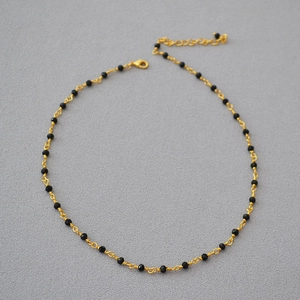Detail of gold chain necklace featuring black spinel beads and adjustable lobster clasp
