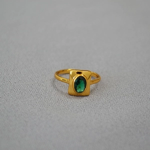 Bague vintage en laiton doré avec une émeraude ovale sur un support en métal brossé