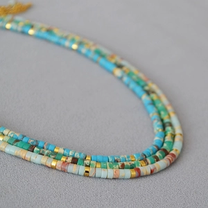 Close-up of colorful stone beads and gold metal spacers in a boho layered necklace