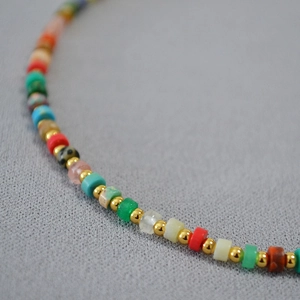 Macro detail of vibrant natural stone beads mixed with golden metallic spacer beads