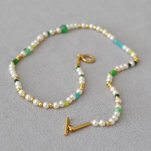 Detail view of irregular freshwater pearl necklace with colorful beads and golden toggle clasp