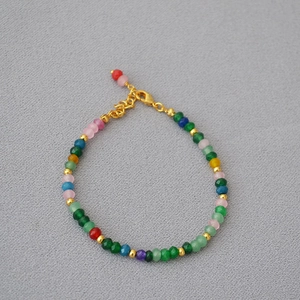 Gros plan du bracelet en perles arc-en-ciel avec pierres d'agate et détails dorés