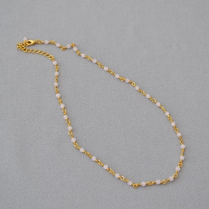 Macro view of dainty pink beaded necklace with gold wire wrap and adjustable lobster clasp