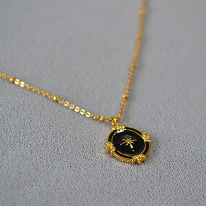 Macro view of French vintage black enamel oval pendant necklace with gold star detail