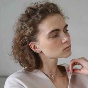 Detail of a minimalist T-bar toggle necklace and mixed-metal ear cuff on model