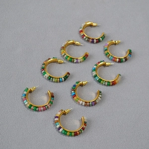 Flat lay of colorful stone beaded C-shaped hoop earrings with gold metal finish