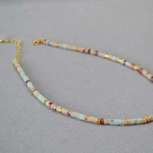 Detail of handcrafted beaded necklace with blue stones and gold metal accents