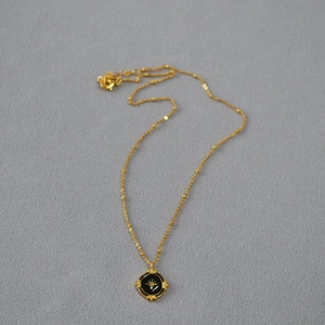 Detail of vintage gold necklace featuring a black enamel oval North Star pendant