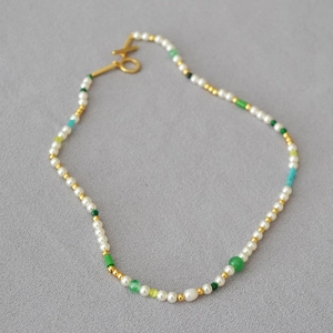 Detail of freshwater pearls and green stone beads necklace with golden OT clasp closure