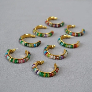 Detailed grid view of seven pairs of C-shaped hoop earrings with colorful beads and gold finish