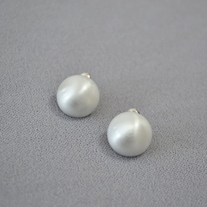 Detailed view of matte pearl dome earrings with brushed silver backing and elegant texture
