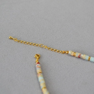 Detail of square natural stone beads and gold lobster clasp on beach style necklace
