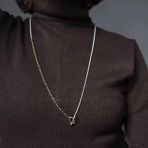Close-up of minimalist layered chain necklace with gold T-bar toggle clasp detail