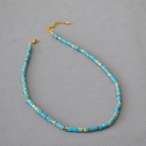 Close-up of ocean-style beaded necklace with blue textured stones and gold metal accents