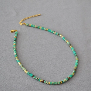 Close-up of turquoise stone beads mixed with golden metal spacers on a beaded necklace