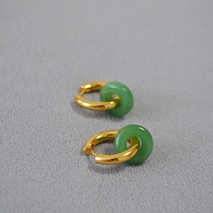 Gros plan de boucles d'oreilles en laiton doré avec des anneaux en jade vert synthétique
