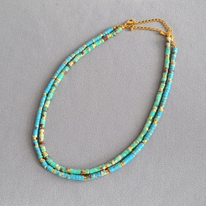 Close-up of bohemian double-layered necklace with blue turquoise beads and gold spacers