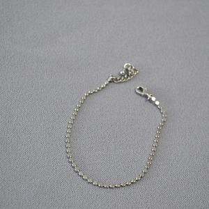 Detailed close-up of shiny silver beaded chain bracelet with adjustable lobster clasp