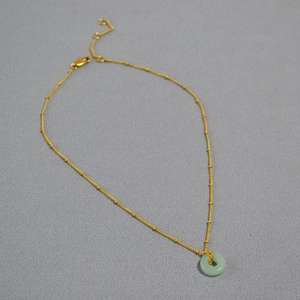 Détail du collier avec pendentif en jade, chaîne dorée et fermoir mousqueton réglable
