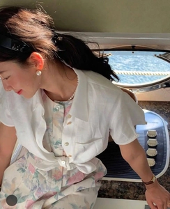 Detail of vintage large faux pearl earrings set against a stylish summer resort outfit