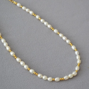 Collier de style français avec perles d'eau douce et billes dorées sur fond gris