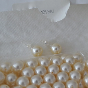Close-up of champagne faux pearl stud earrings with 925 silver needles on pearl background