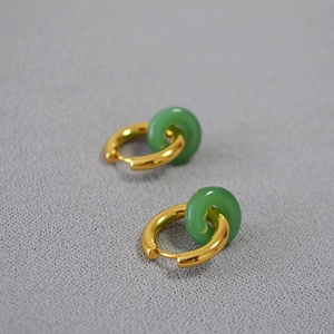 Détail de boucles d'oreilles créoles en laiton doré avec pendentifs en pierre verte