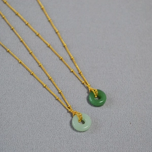 Détail de pendentifs en jade poli sur des chaînes plaquées or avec perles satellites