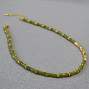 Detail showing green jade bamboo joints with gold beads on a minimalist necklace