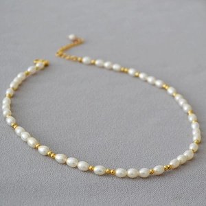 Détail de perles de riz d'eau douce avec billes dorées et fermoir mousqueton réglable