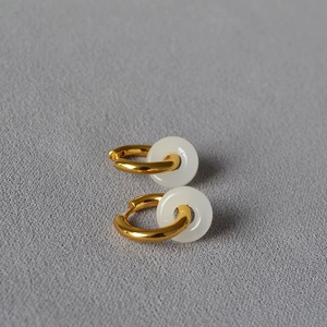 Détail des boucles d'oreilles créoles dorées avec pendentifs en jade blanc Pingan