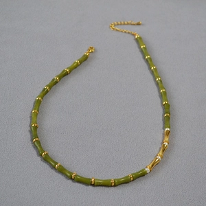 Detail of bamboo-style necklace with green beads, golden accents and pearl charms