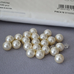 Macro shot of 100 cream faux pearls on grey felt with silver earrings and backings