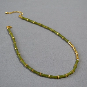 Detailed view of bamboo-shaped green jade necklace with gold accents and pearl details