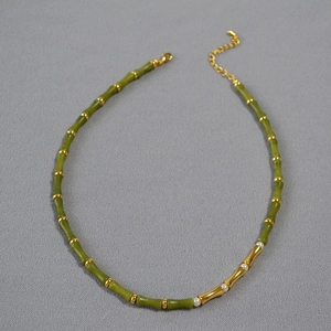 Macro detail of bamboo-style green beaded necklace with gold metal accents and pearls