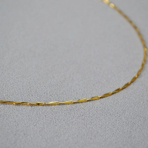 Macro view of dainty 18k gold-plated brass chain necklace with high-shine finish