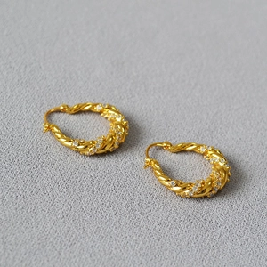Macro detail of gold twisted rope hoop earring with micro-paved sparkling zircon stones